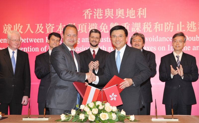 Professor Chan (right, front row) exchanges documents with Mr Schieder after signing the agreement.