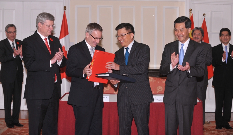 Professor Chan (second right) exchanges documents with Mr Fast (second left) after signing the agreement. 