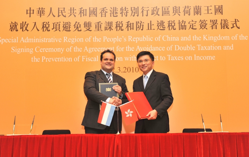 陳家強(右)與DeJager在簽訂香港特別行政區與荷蘭之間的全面性避免雙重徵稅協定後，互相交換文件。